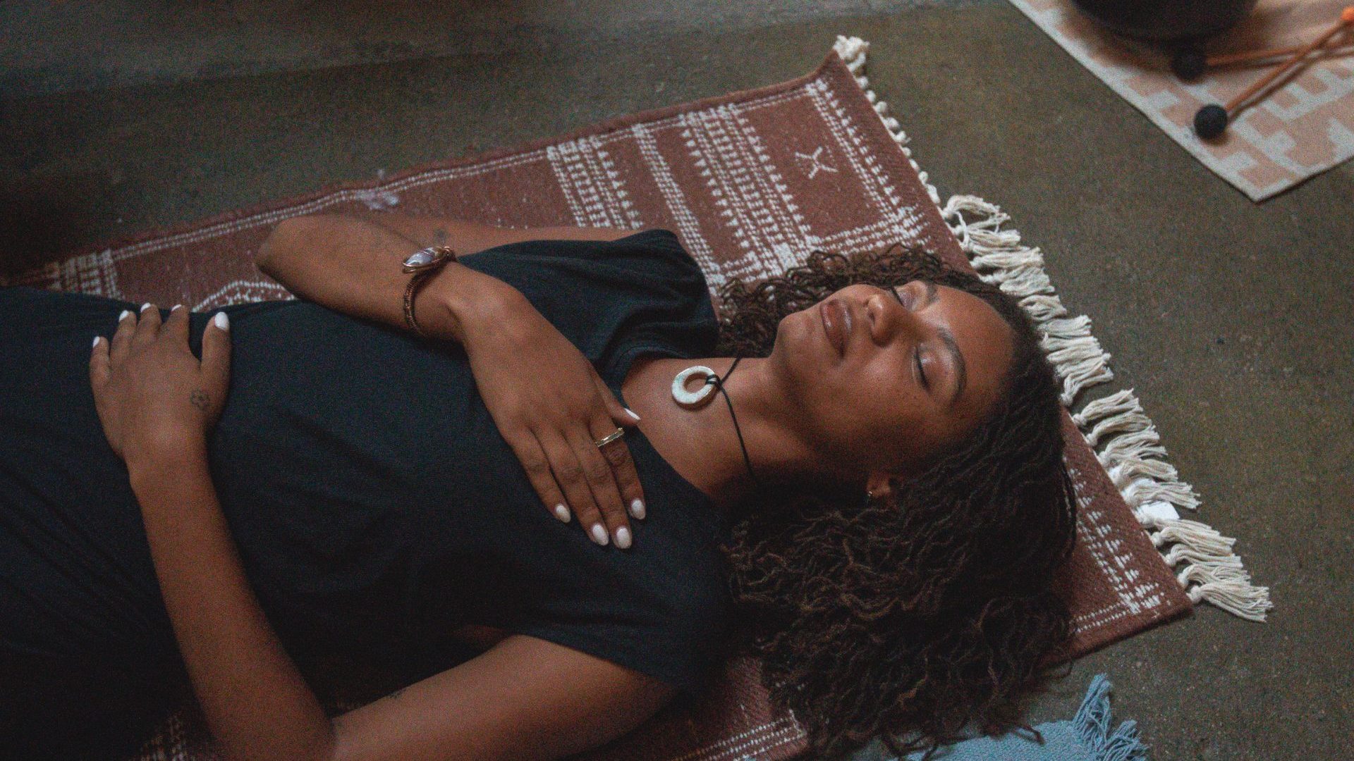 Woman lays on floor, eyes closed, during meditation