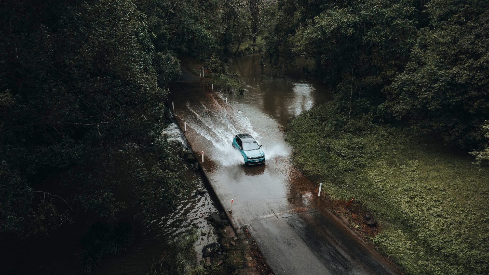 Aerial shot of car driving across bridge of water