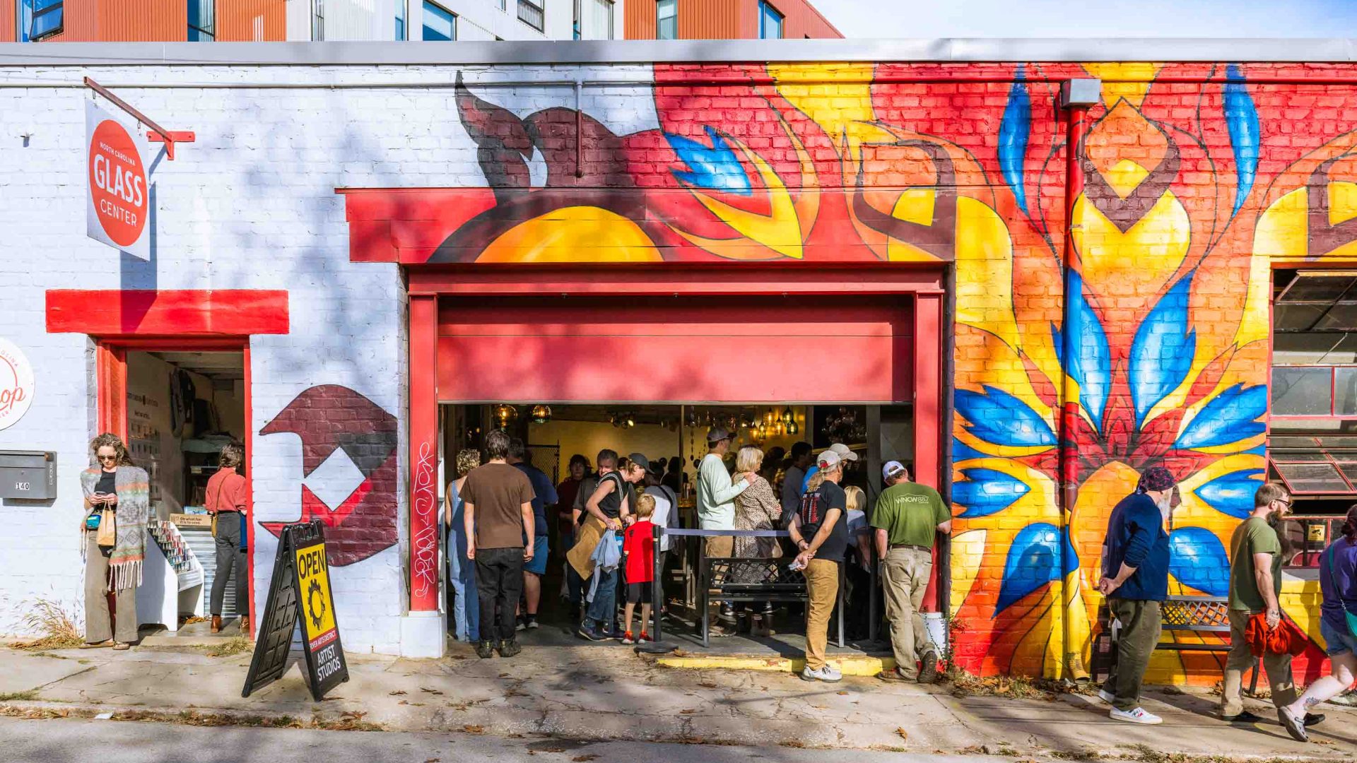 Crowds at a festival inside a building decorated with a bright mural