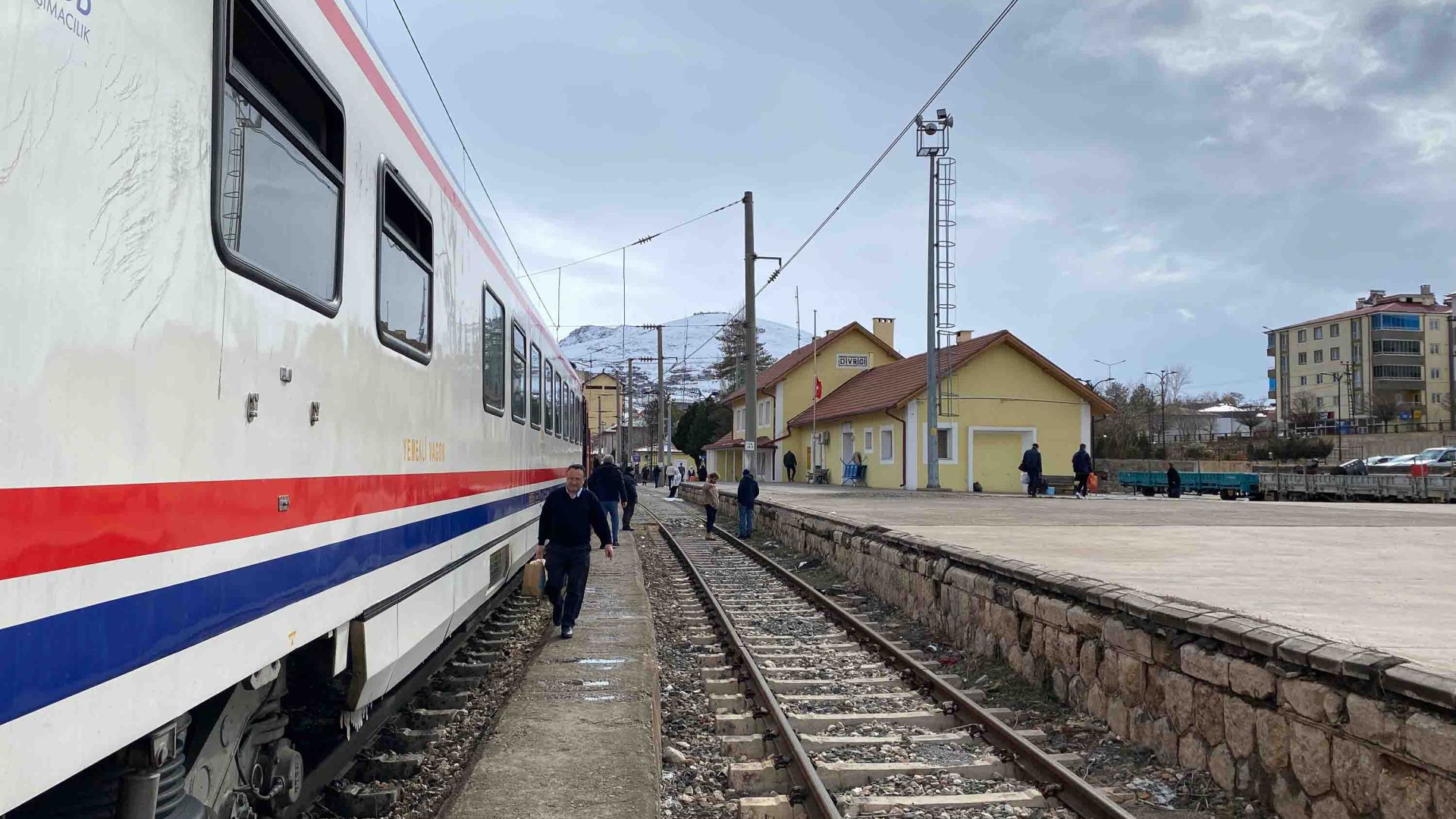 A train is pulled up at a platform as passengers walk alongside it
