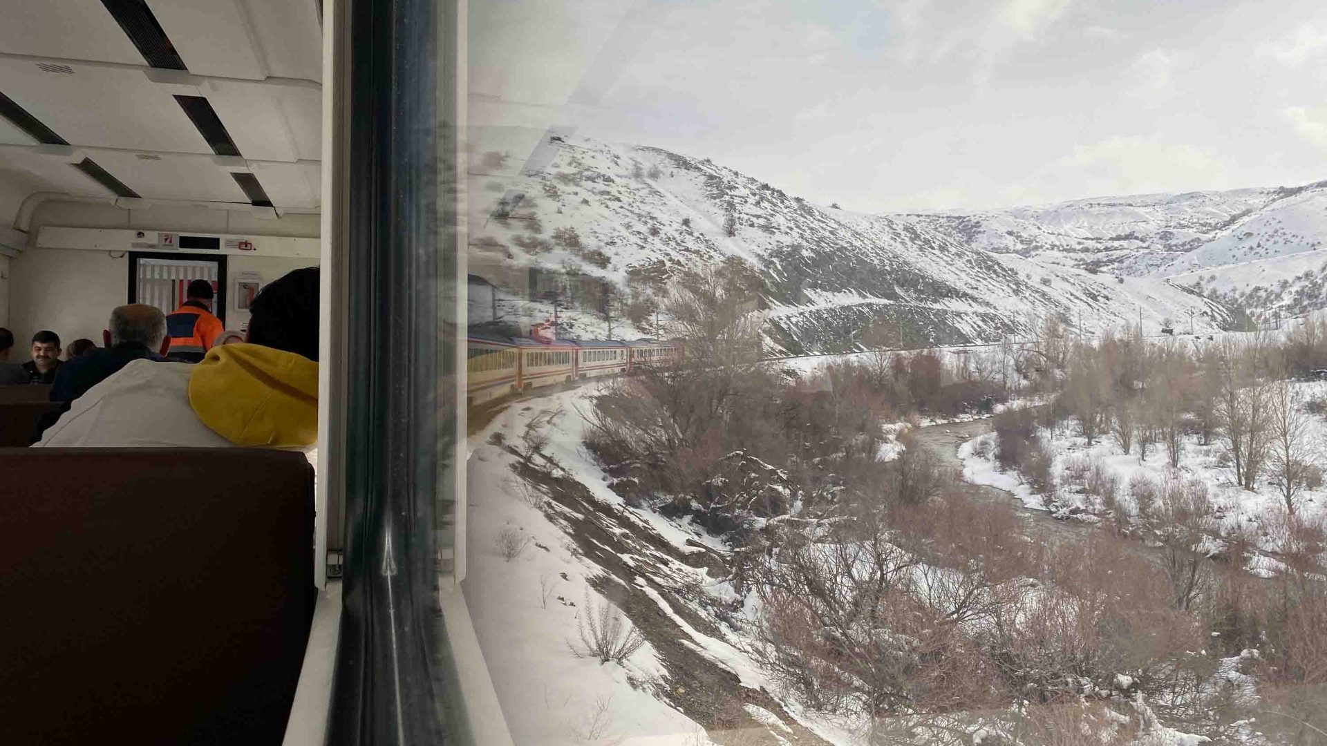 To the left, the interior of the train carriage as the train cruves around a river against a snowy mountain backdrop.