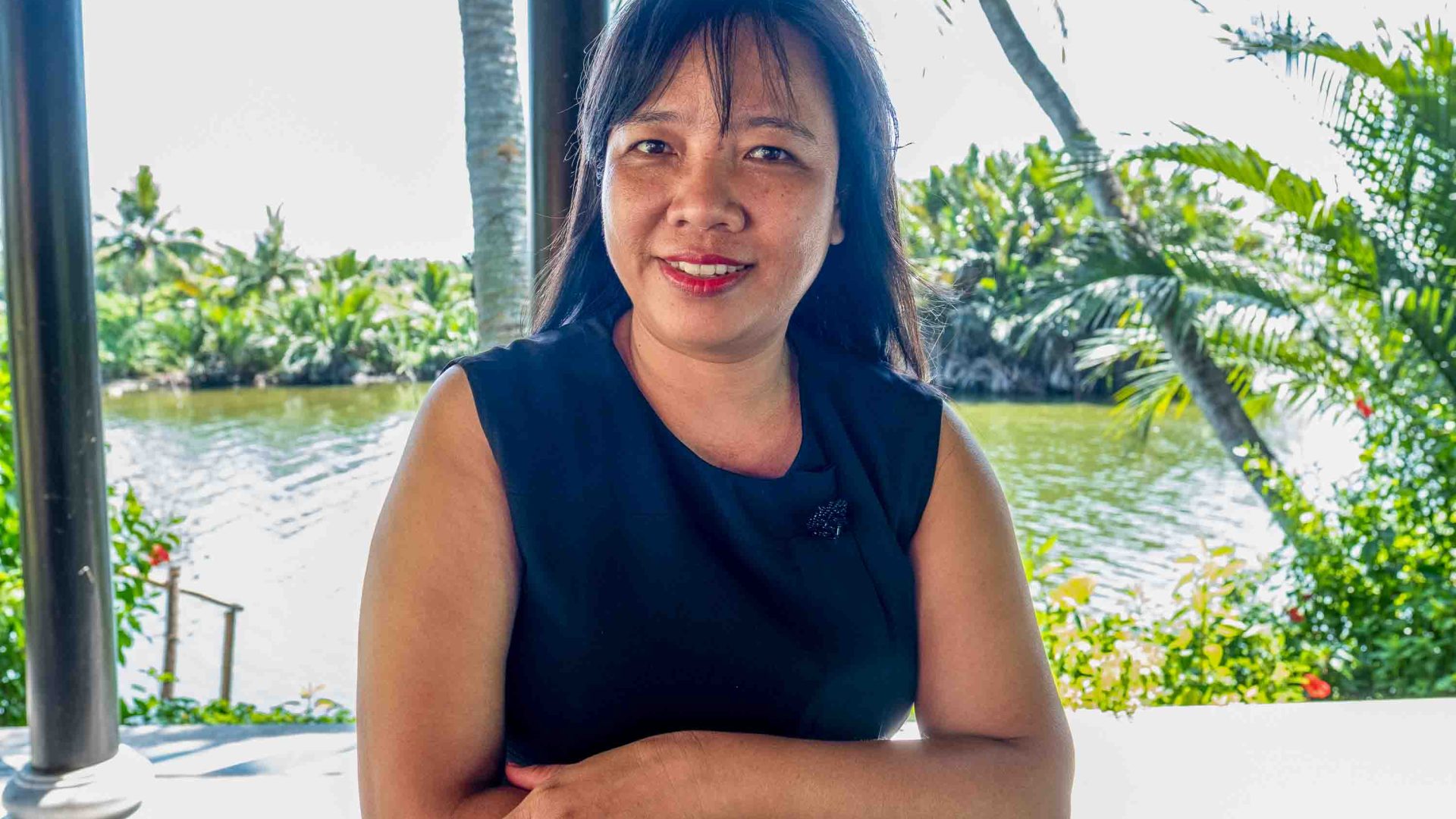 A woman sits at a table and smiles to camera.