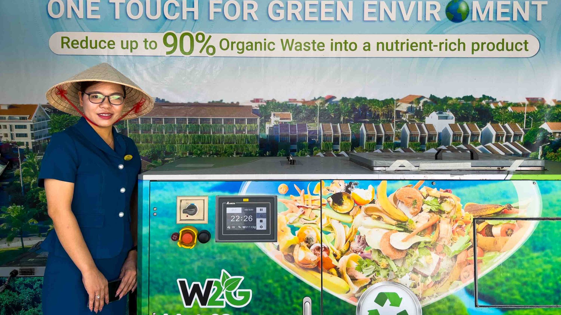 A woman stands next to a food waste chomper.