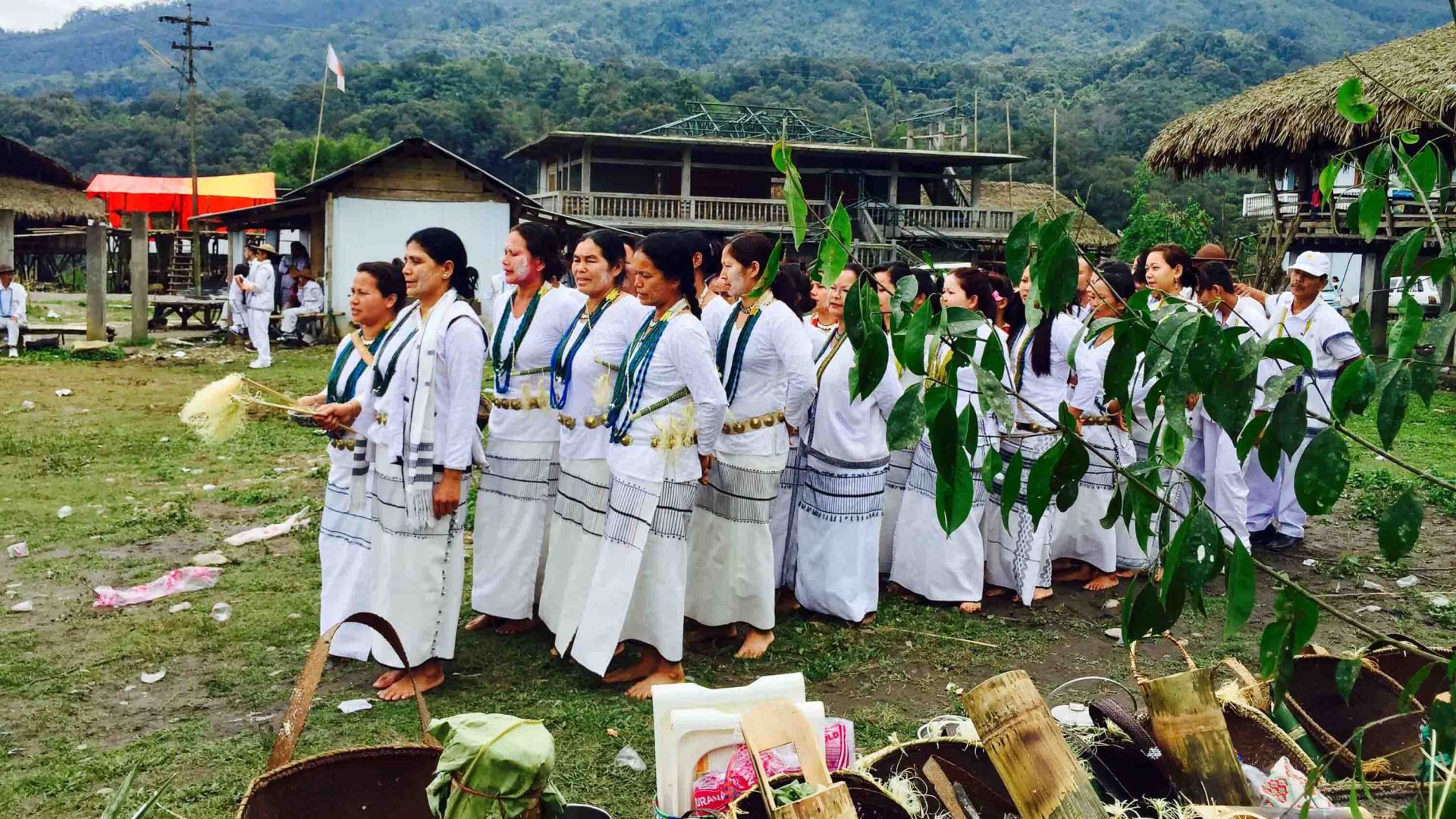 Performers in traditional white clothing in a village.