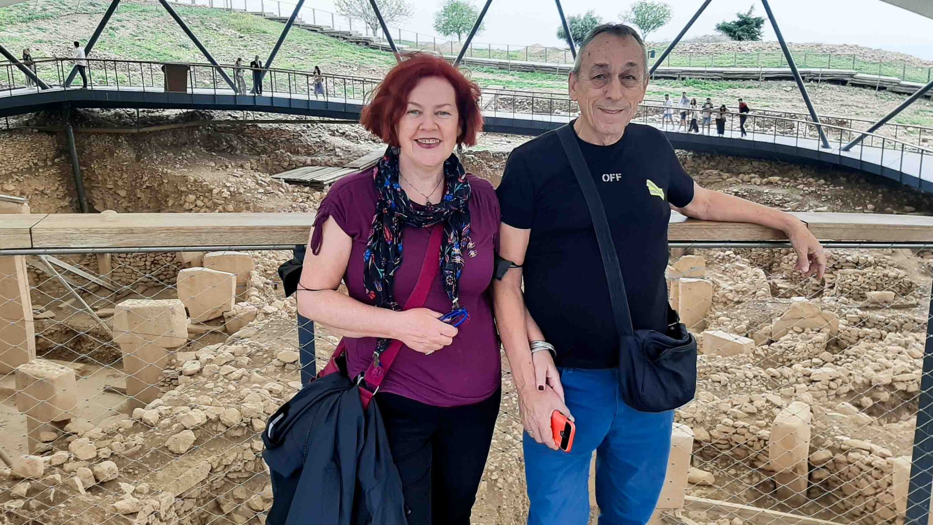 A woman and man stand in front of some ruins.