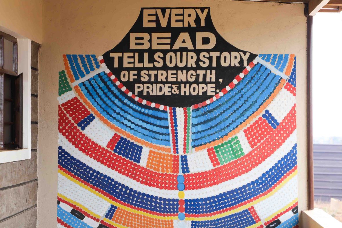 A mural of a beaded necklace with the words 'Every bead tells our story of strength, pride and hope'.