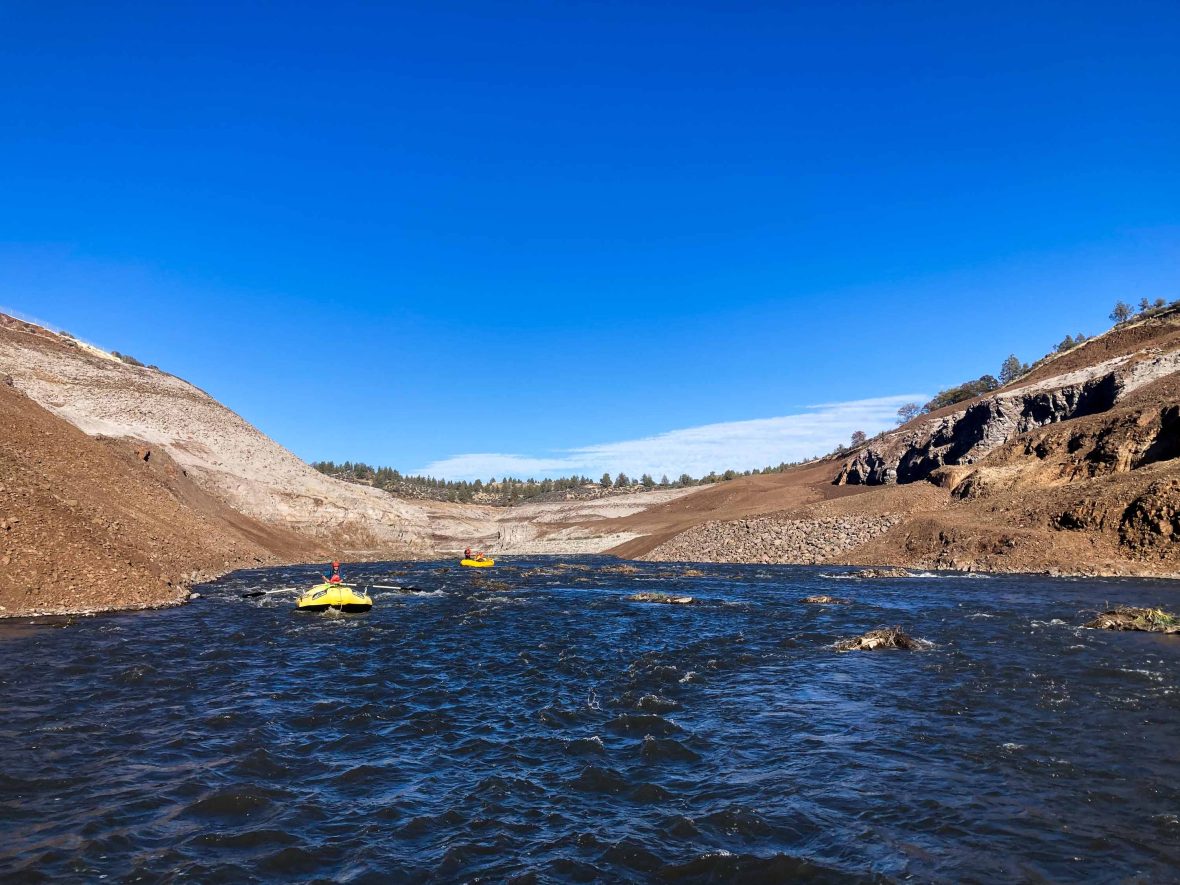 Rafts move down a part of the river with barren sides.