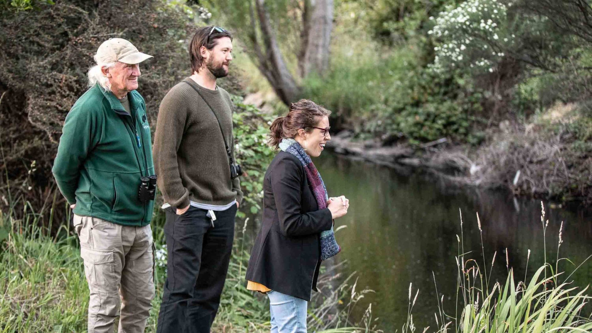 Three people look at a river.