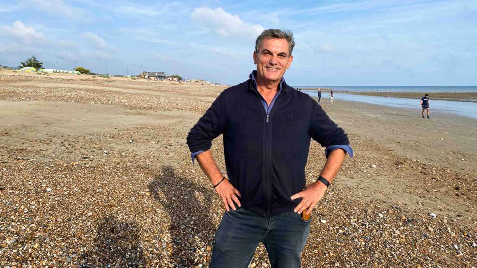 A man smiles with his hands on his hips.