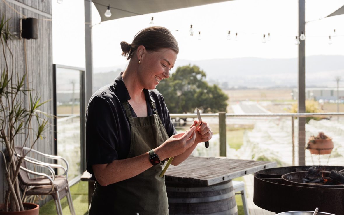 A woman chops a vegetable in an open-air kitchen