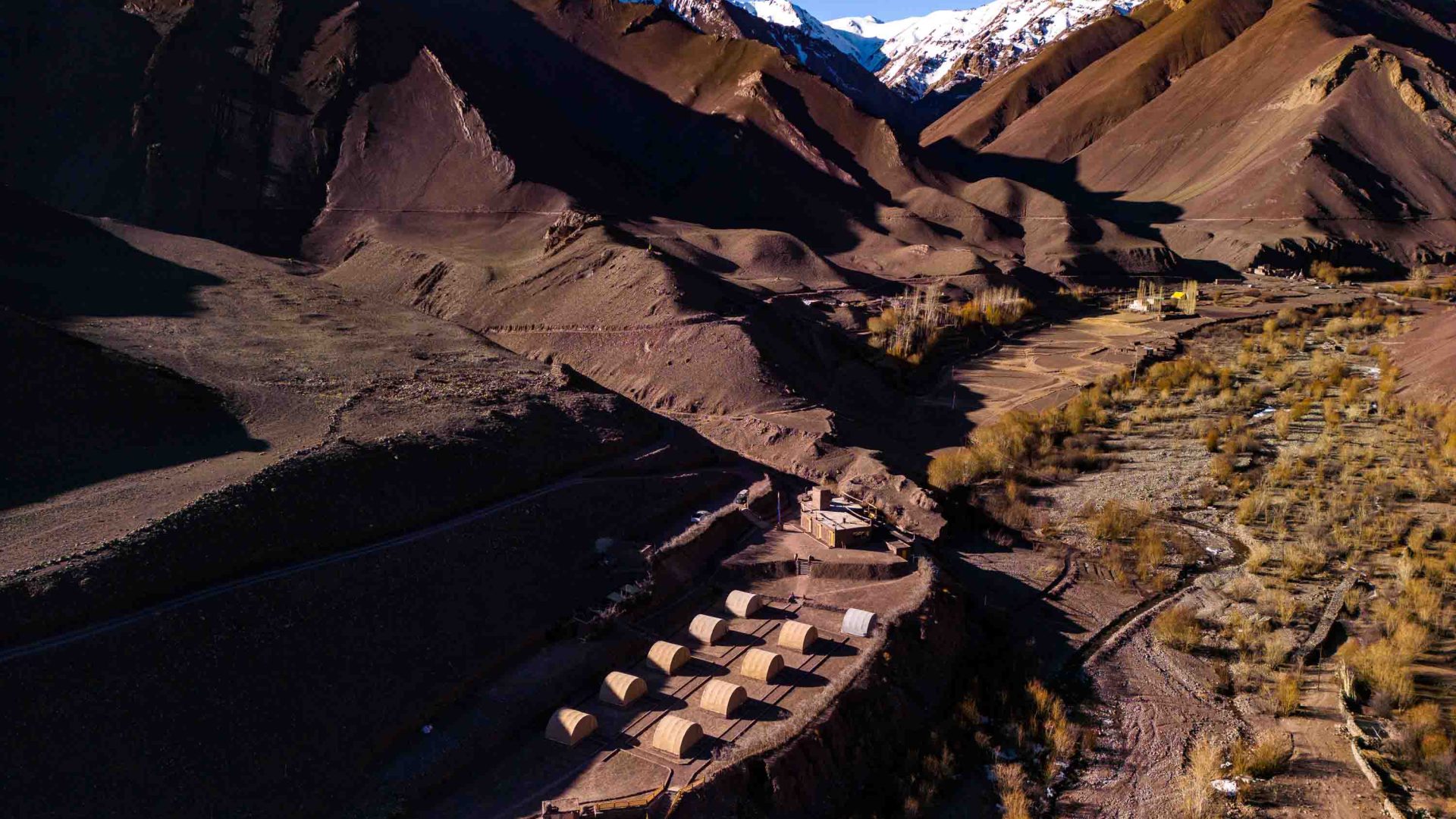 A camp is surrounded by red coloured mountains.