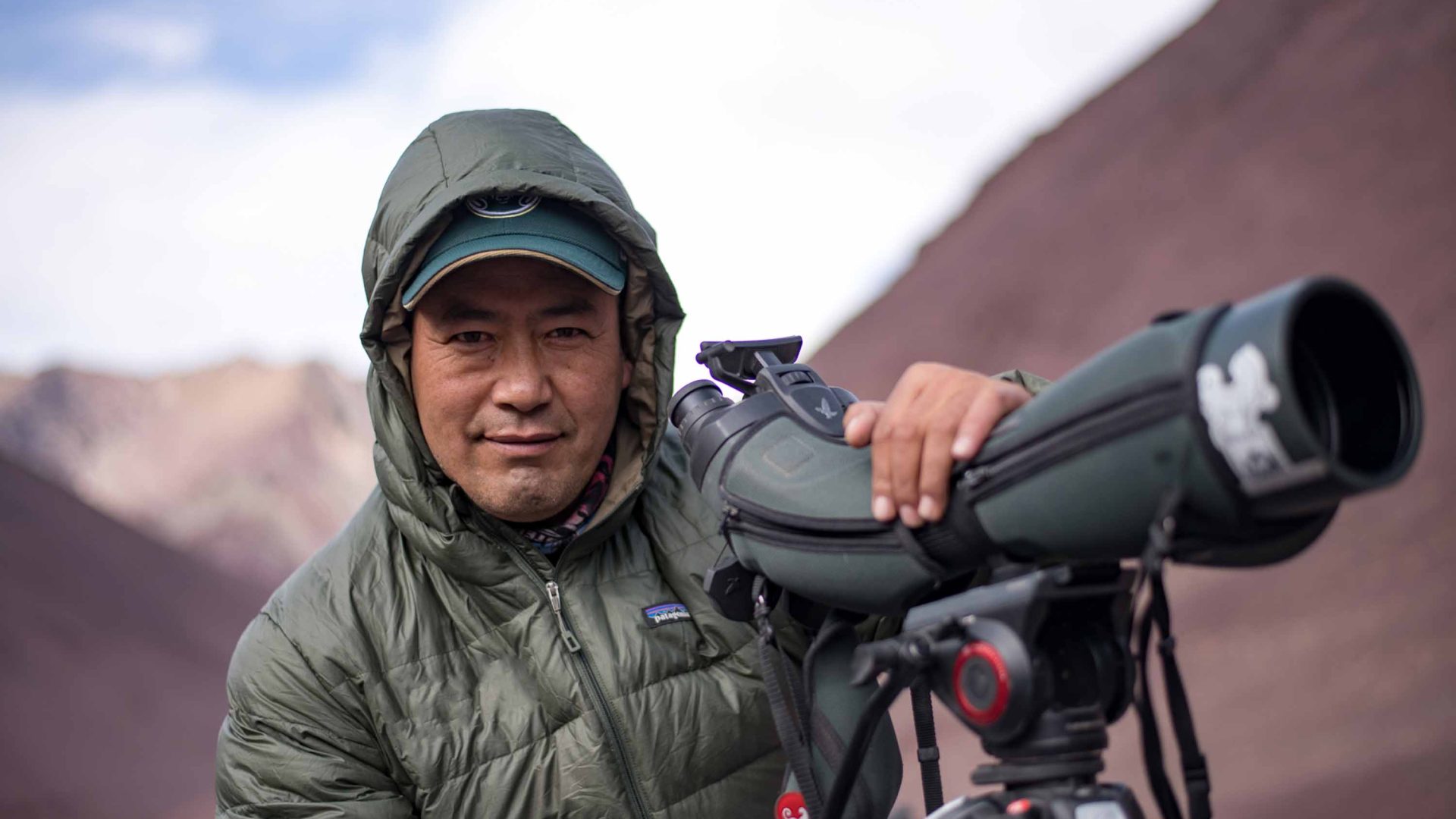 A snow leopard tracker uses a scope to look for leopards.