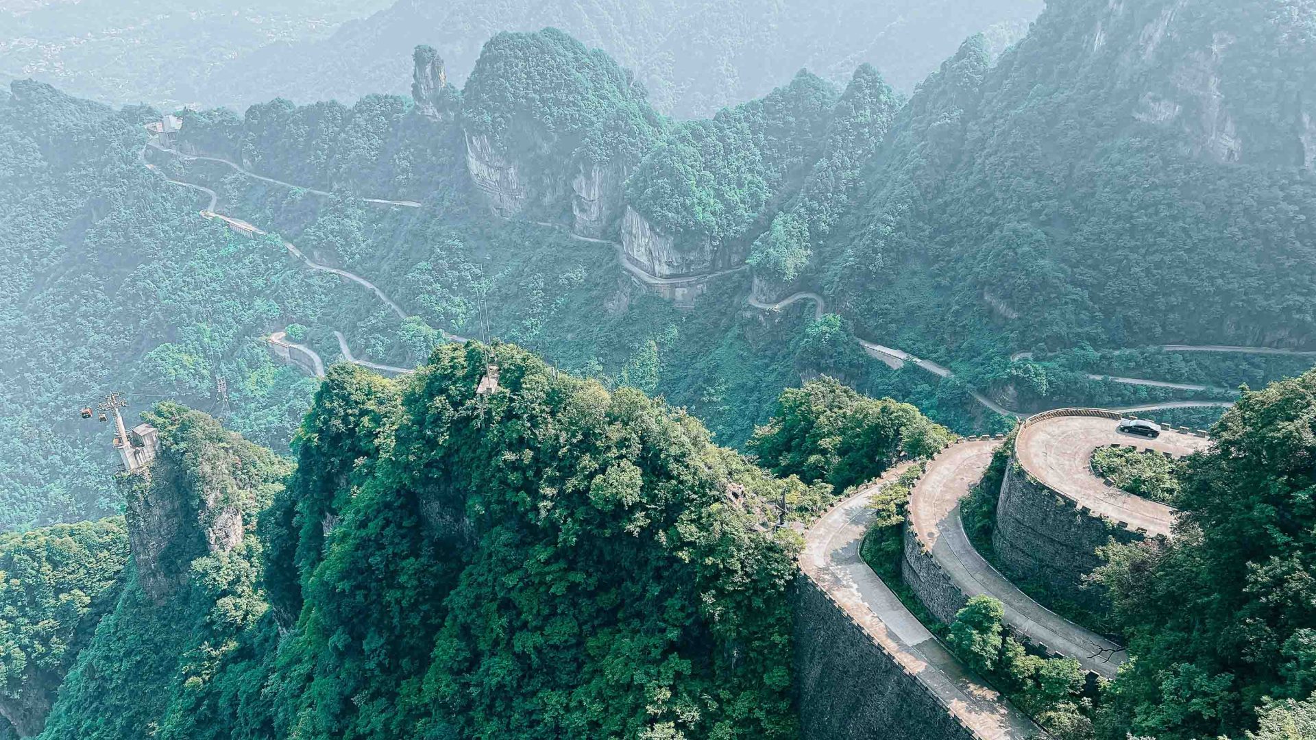 A road winds around green mountains.